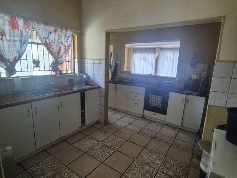 A functional kitchen featuring built-in cabinetry, tiled flooring, and a tiled backsplash, offering a practical layout with potential for modern updates.