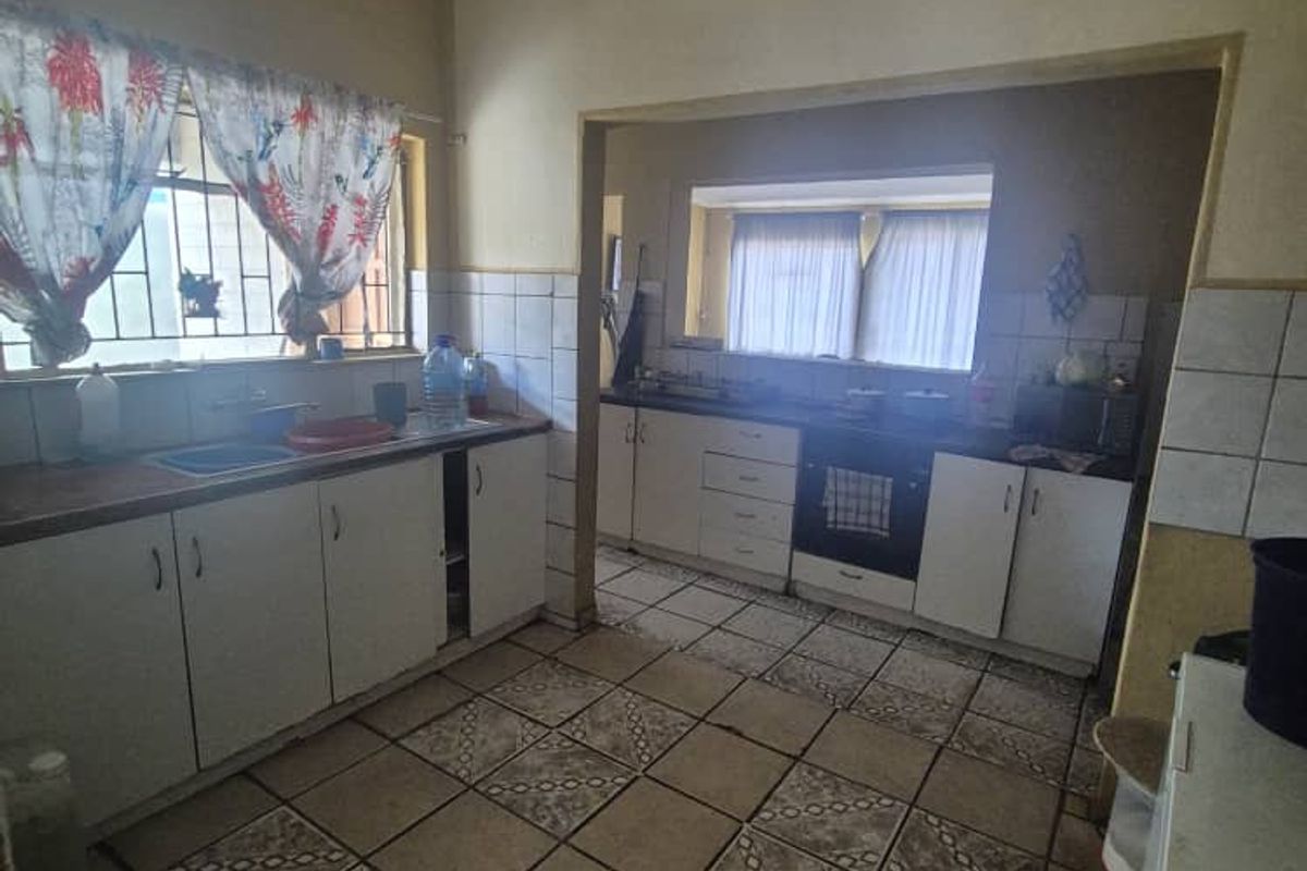 A functional kitchen featuring built-in cabinetry, tiled flooring, and a tiled backsplash, offering a practical layout with potential for modern updates.