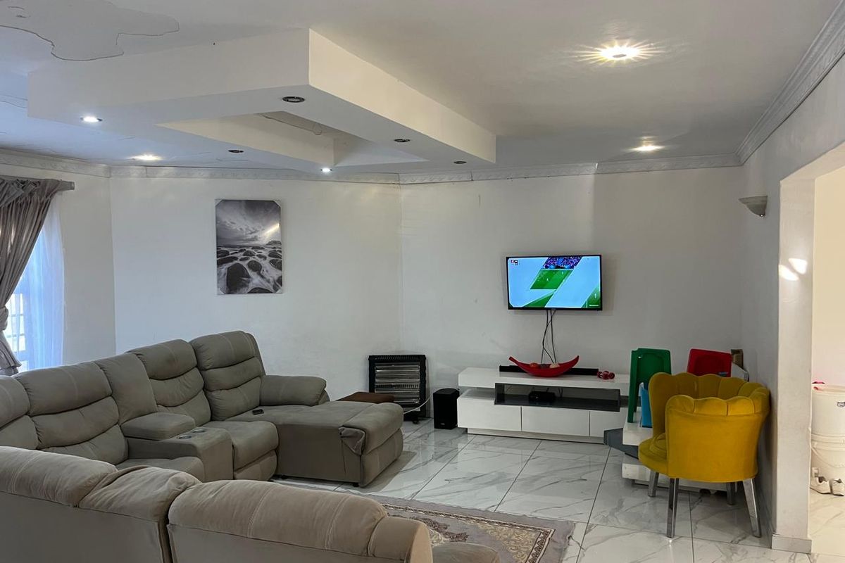 Spacious living room featuring marble-look floor tiles, a recessed ceiling with downlights, and coving detail. Note visible ceiling water staining.