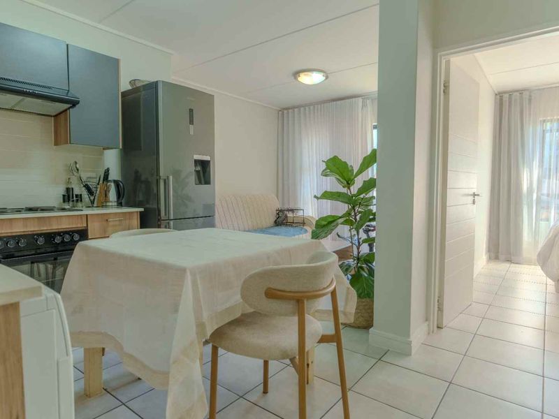 Open-plan living area featuring a compact kitchen with built-in cabinetry and tiled flooring, leading into a bright, connected living space.