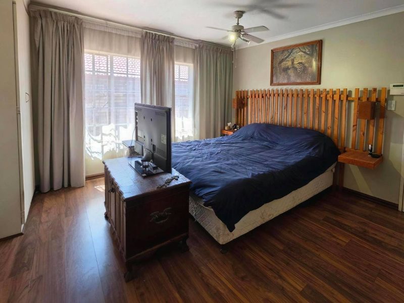 A bedroom featuring laminate flooring, a ceiling fan, and a sliding glass door providing natural light.