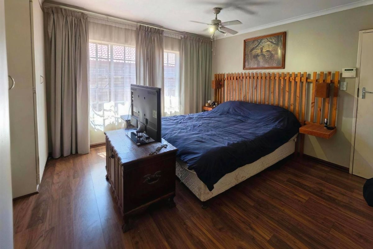 A bedroom featuring laminate flooring, a ceiling fan, and a sliding glass door providing natural light.