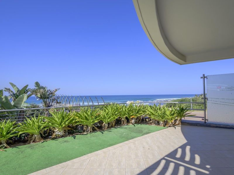 A spacious balcony featuring tiled flooring, a stainless steel balustrade, and a privacy screen, offering expansive ocean views.