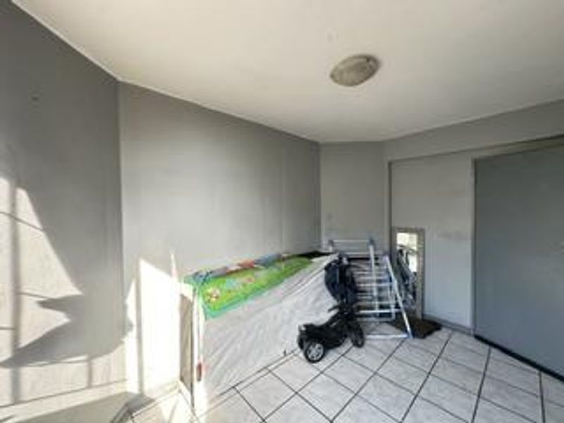 A covered balcony area featuring tiled flooring and neutral wall finishes, providing a functional outdoor space for the apartment.