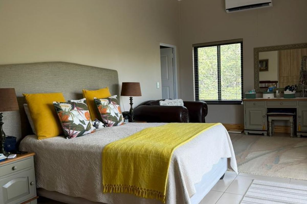 Spacious bedroom featuring tiled flooring, a wall-mounted air conditioning unit, and large windows allowing for natural light.