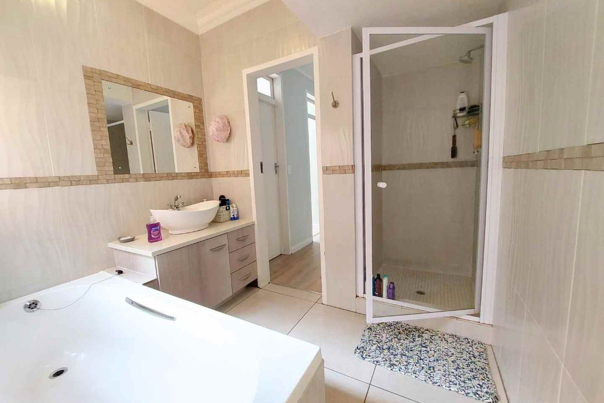 A functional bathroom featuring a built-in bathtub, a separate glass-enclosed shower, and a vanity unit with a vessel sink.