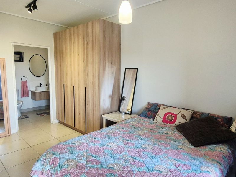 A well-maintained bedroom featuring tiled flooring, built-in wooden wardrobes, and an adjoining en-suite bathroom with modern fixtures.
