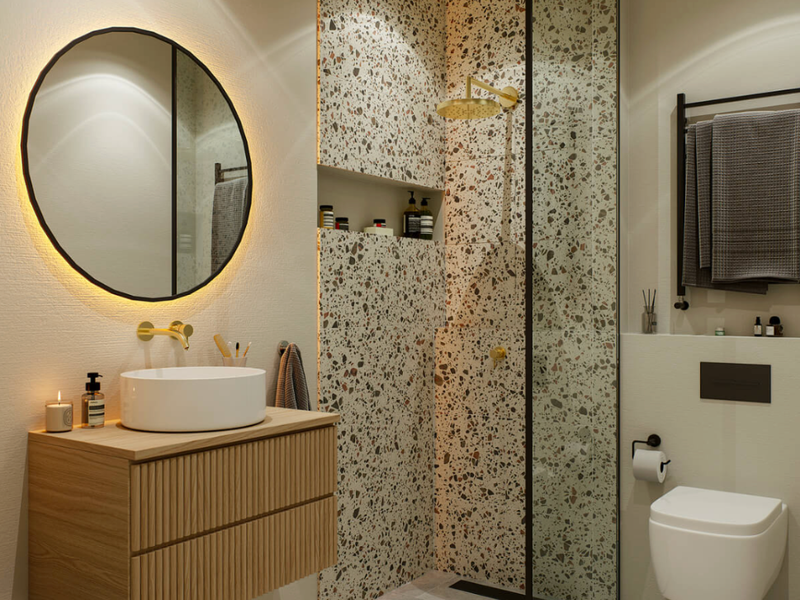 Modern bathroom featuring a wall-mounted vanity, vessel sink, terrazzo-tiled walk-in shower, wall-hung toilet, and elegant backlit circular mirror.