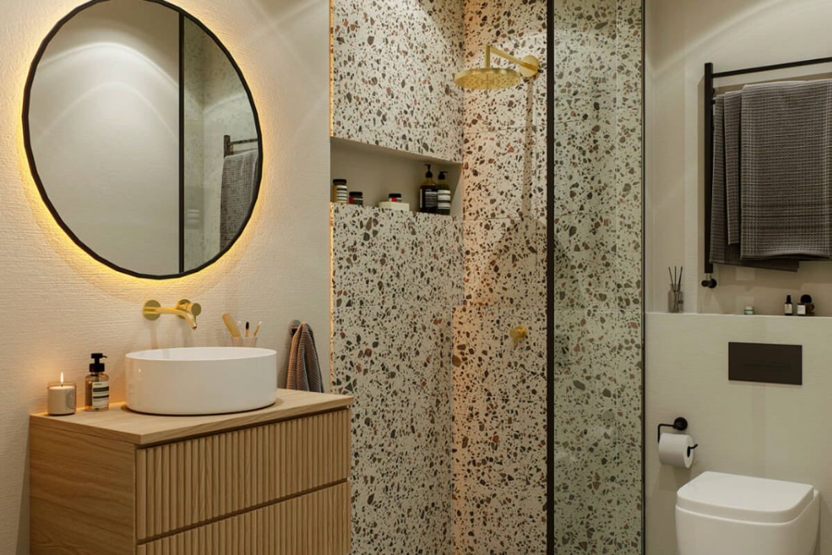 Modern bathroom featuring a wall-mounted vanity, vessel sink, terrazzo-tiled walk-in shower, wall-hung toilet, and elegant backlit circular mirror.