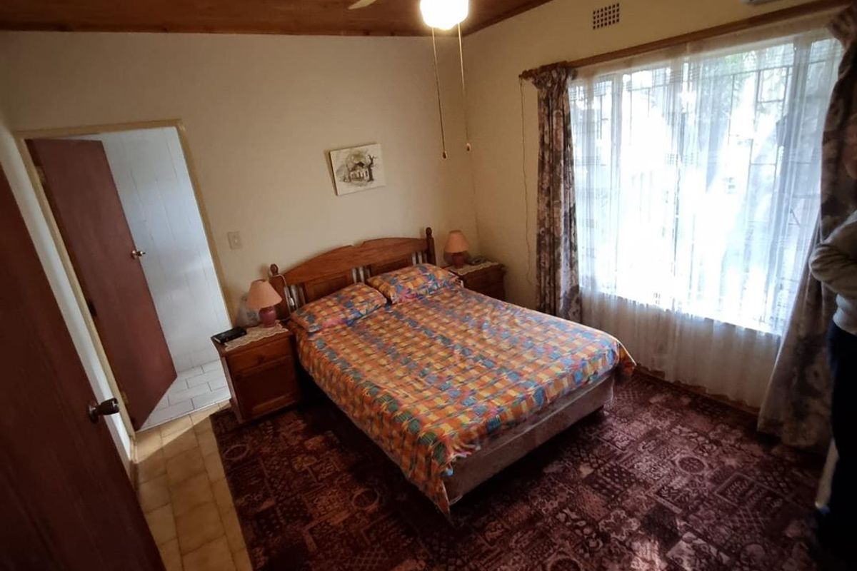 A bedroom featuring a timber ceiling, ceiling fan, and split-system air conditioning unit, with large windows providing natural light.