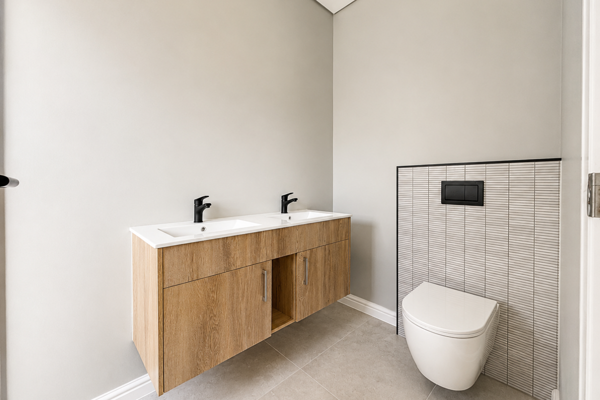 Modern bathroom featuring a wall-mounted double vanity with wood-look cabinetry, black fixtures, and a wall-hung toilet with tiled feature wall.