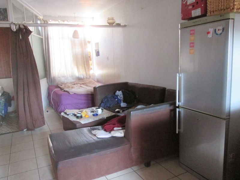 An open-plan living and sleeping area featuring tiled flooring and a partition wall, offering a functional layout for compact apartment living.