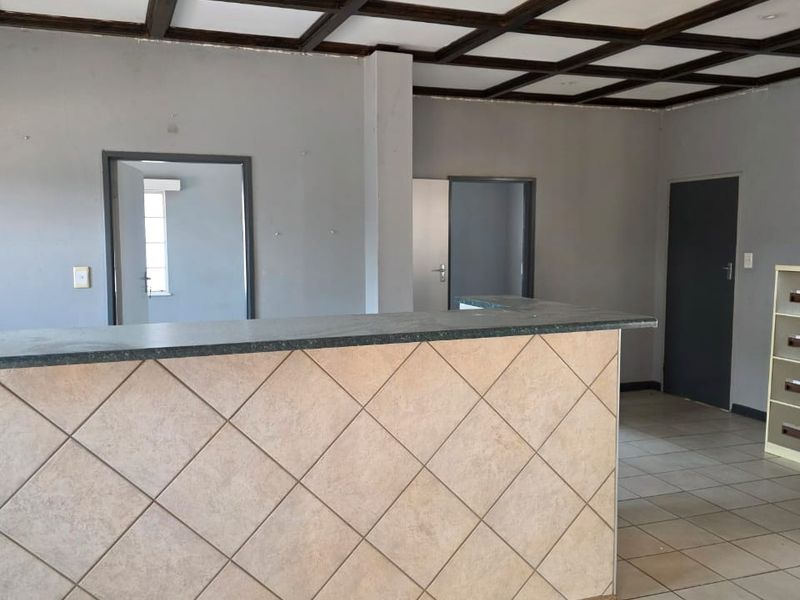 An open-plan industrial space featuring a tiled service counter, coffered ceiling with recessed lighting, and ceramic floor tiles throughout.