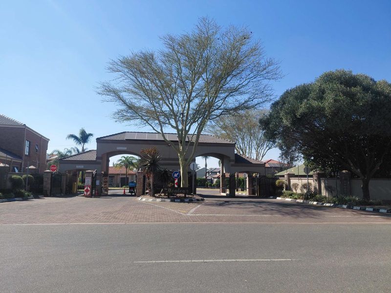 The main entrance gatehouse to The Meadows estate, featuring a paved driveway, secure access point, and established landscaping.