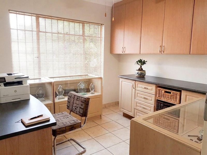 A functional office space featuring built-in cabinetry, laminate countertops, and ceramic tile flooring, providing ample storage and workspace.