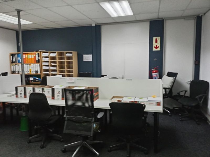 A functional office space featuring a suspended ceiling, recessed lighting, and built-in shelving, providing a practical work environment.