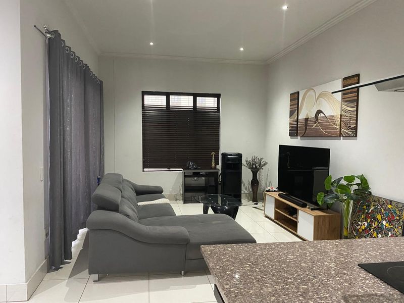 Open plan living area featuring tiled flooring, recessed downlights, and a granite kitchen countertop, creating a functional and connected space.