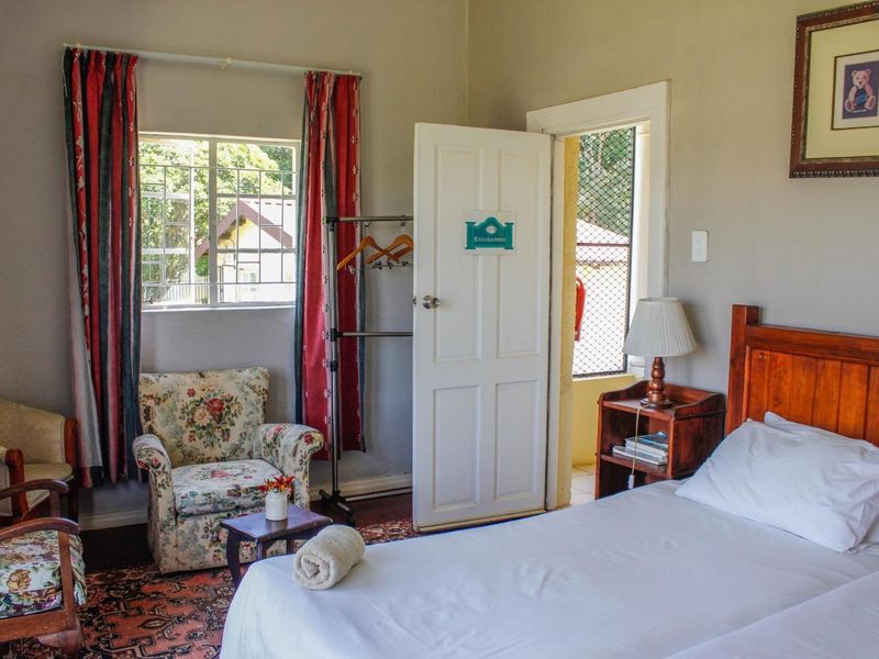 A bedroom featuring a window with security bars, a panel door leading to an exterior area, and neutral wall finishes.