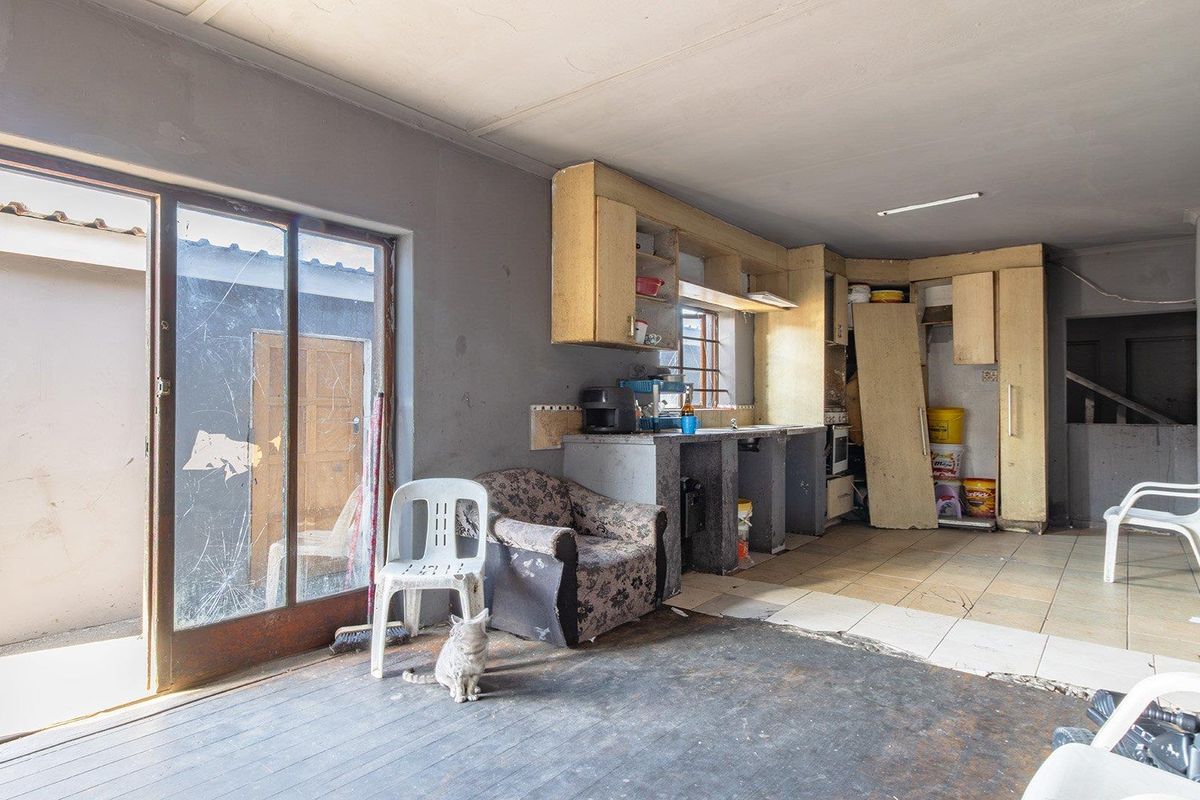 A kitchen area featuring built-in cabinetry and tiled flooring, currently requiring significant maintenance and cosmetic updates to restore its functionality and appeal.