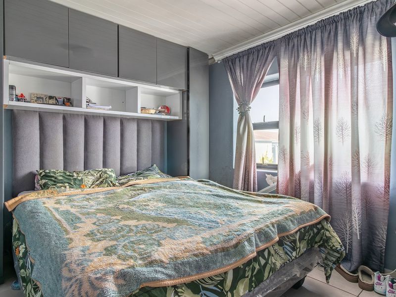 A bedroom featuring built-in grey cabinetry with overhead storage, an integrated upholstered headboard, tiled flooring, and a tongue and groove ceiling.