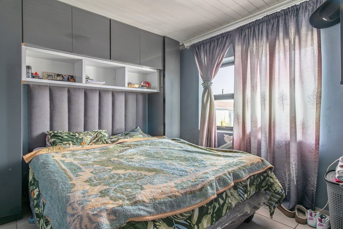 A bedroom featuring built-in grey cabinetry with overhead storage, an integrated upholstered headboard, tiled flooring, and a tongue and groove ceiling.
