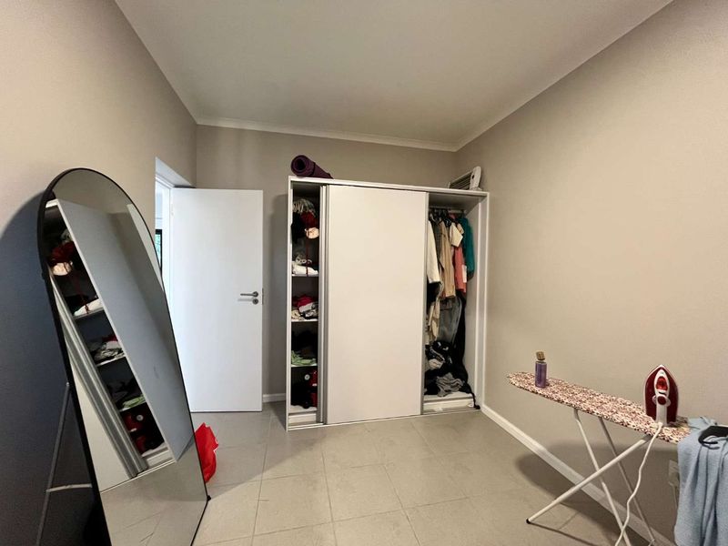 A bedroom featuring tiled flooring, a built-in wardrobe with sliding doors, and an integrated air conditioning unit.