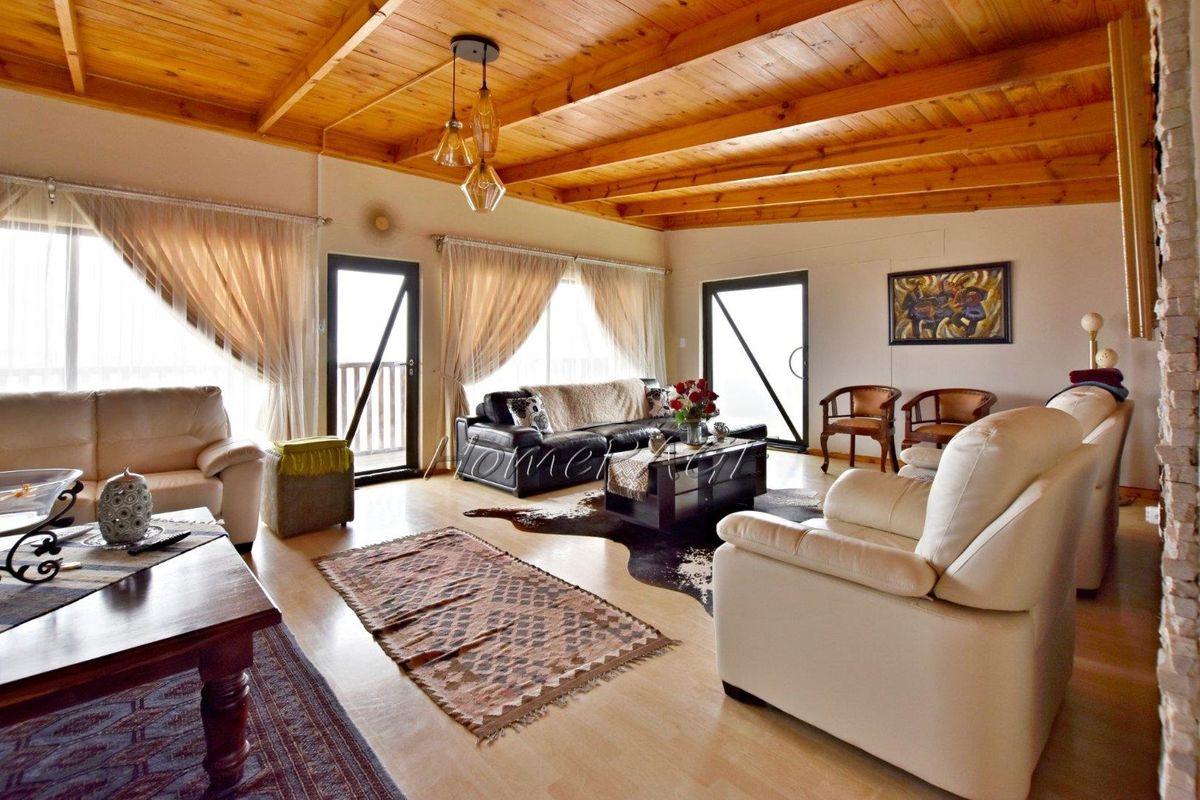 Spacious living room featuring exposed timber beam ceilings, large sliding glass doors providing natural light, and neutral flooring.