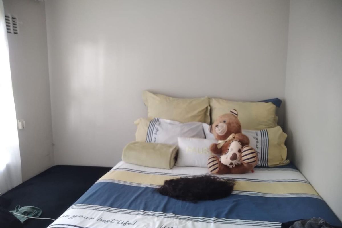 A standard bedroom featuring neutral wall finishes and carpeted flooring, providing a functional and simple living space.