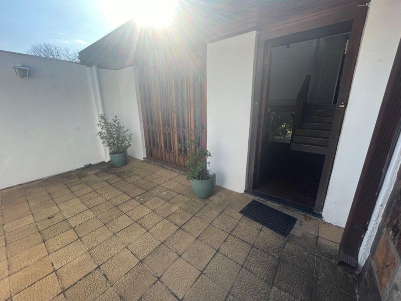 A paved outdoor patio area featuring a security gate and direct access to the interior, providing a functional entrance or outdoor space.