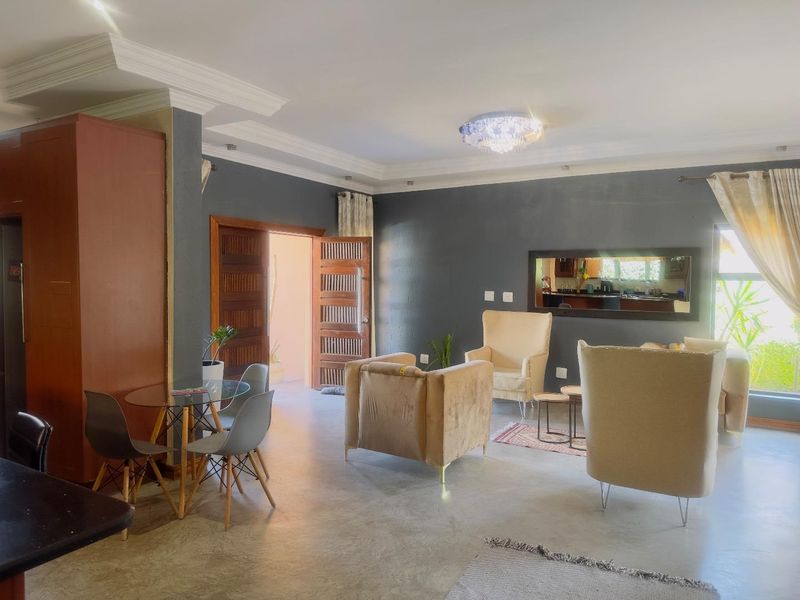 Spacious living area featuring polished concrete flooring, decorative crown molding, and a large built-in wall mirror, providing a bright and open atmosphere.