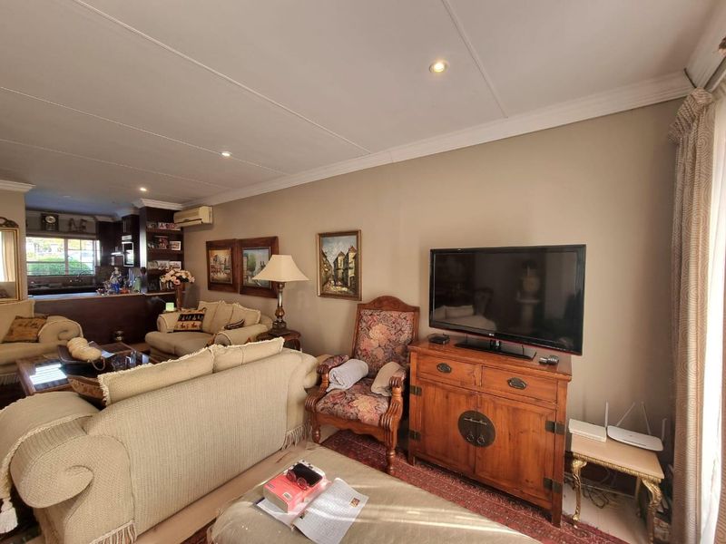Open-plan living area featuring recessed lighting, coved cornicing, and a split-system air conditioner, flowing into a kitchen space with built-in cabinetry.