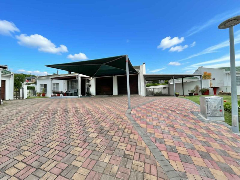 Front exterior view featuring a large paved driveway, double garage, and a shade sail carport providing covered parking space.