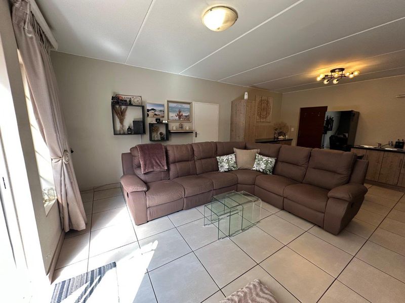 Open-plan living area featuring tiled flooring and integrated kitchen space with cabinetry, offering a functional layout for modern townhouse living.