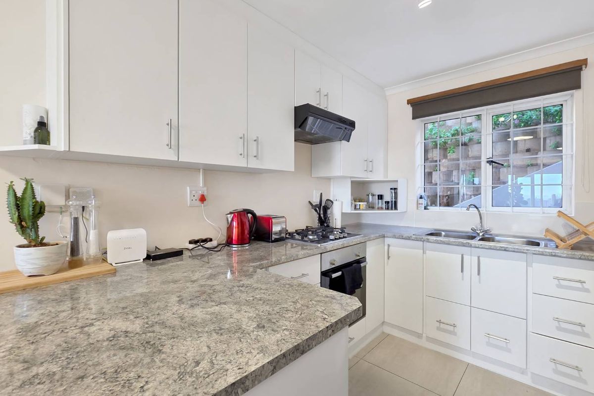 A well-maintained kitchen featuring white cabinetry, granite-look countertops, a gas hob, built-in oven, and a functional layout with ample storage.