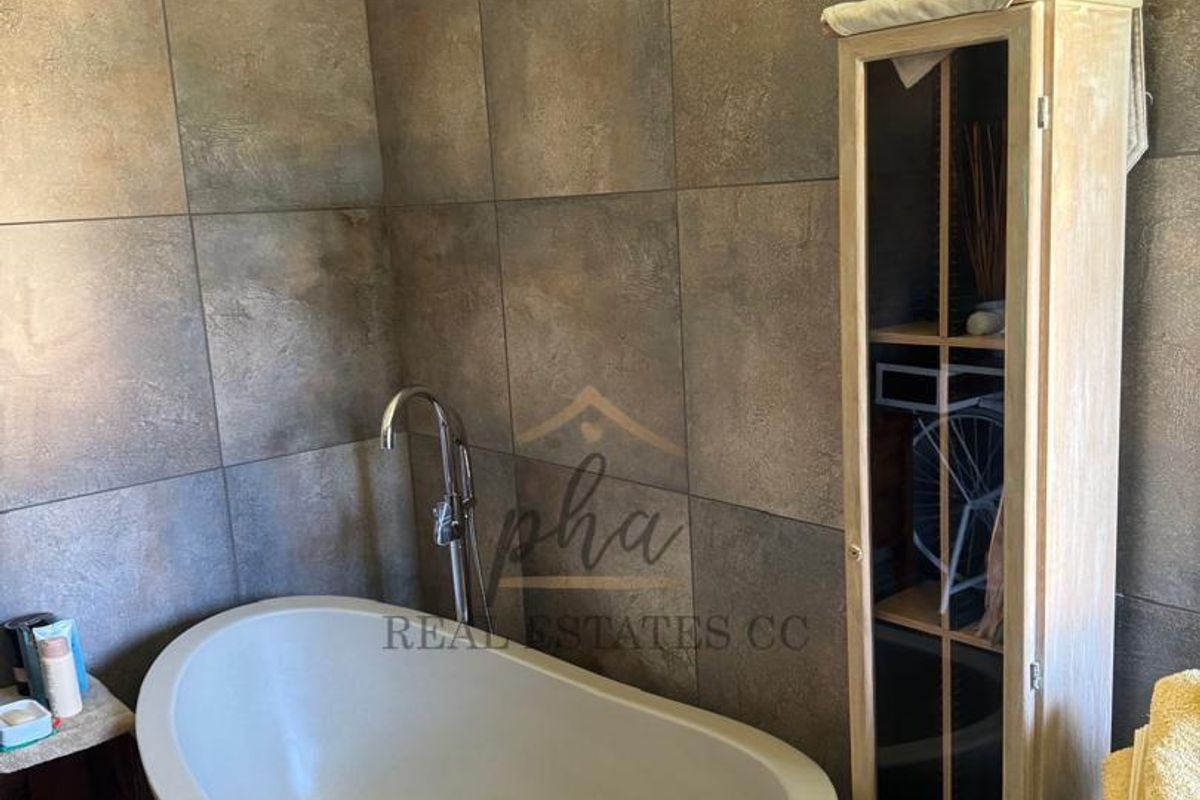 A modern bathroom featuring a contemporary freestanding bathtub with a sleek floor-mounted mixer tap and large format textured wall tiling.