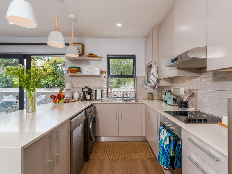 Modern kitchen featuring quartz countertops, integrated cabinetry, built-in oven, electric hob, and a tiled backsplash, with direct access to an outdoor balcony area.