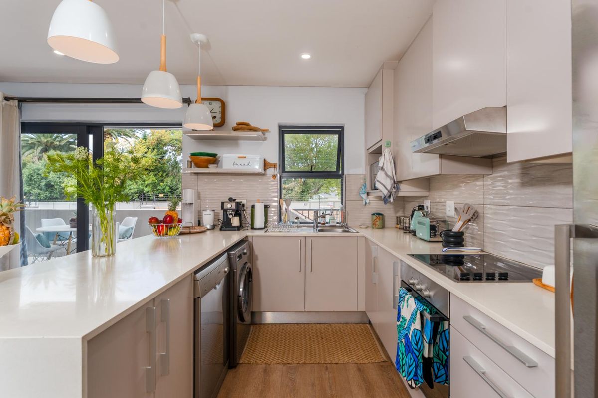 Modern kitchen featuring quartz countertops, integrated cabinetry, built-in oven, electric hob, and a tiled backsplash, with direct access to an outdoor balcony area.