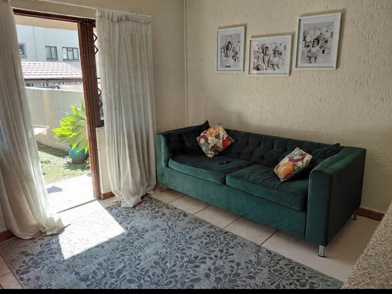 A living room featuring tiled flooring, textured walls, and a sliding glass door providing direct access to the outdoor area.