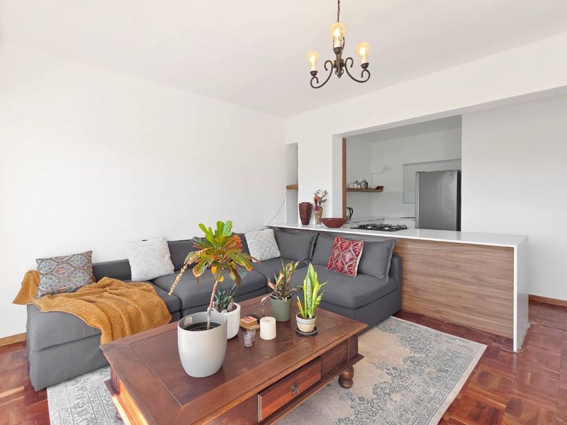 Open-plan living area featuring warm parquet flooring, a modern breakfast bar, and a functional kitchen space with a built-in gas hob.