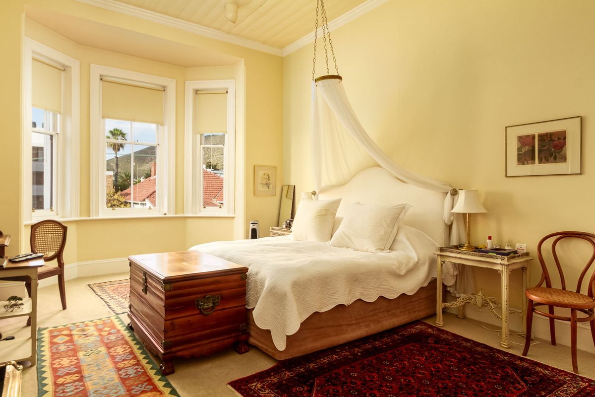 A bright bedroom featuring a classic bay window, tongue and groove ceiling, and elegant crown molding, offering a warm and inviting atmosphere.
