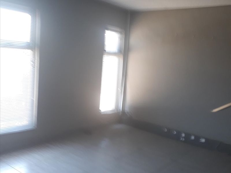 An empty office space featuring tiled flooring, recessed ceiling lighting, and windows fitted with venetian blinds.