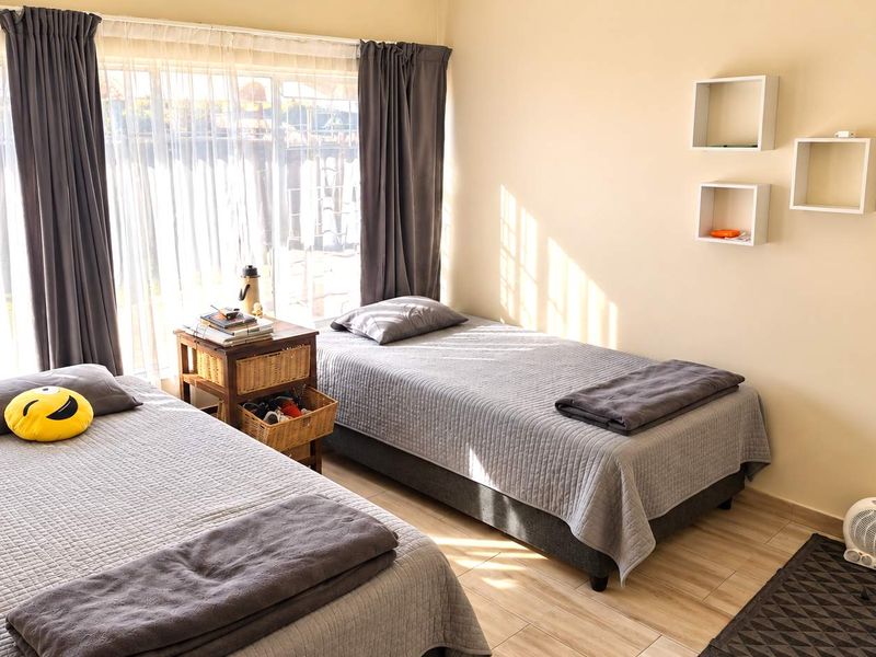 A bright bedroom featuring tiled flooring, large windows allowing natural light, and wall-mounted shelving units.