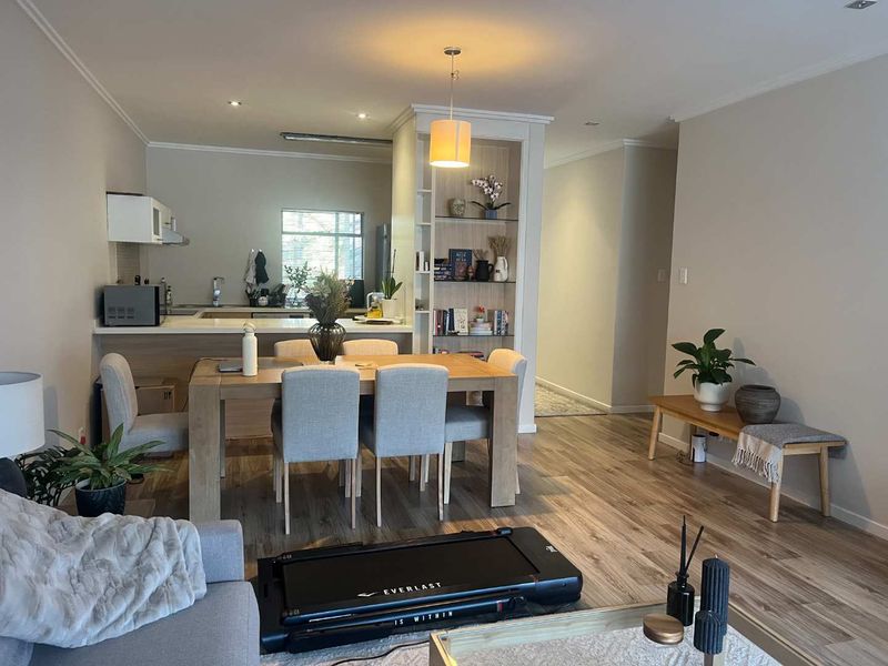 Open-plan living and dining area featuring modern laminate flooring, a built-in display shelf, and a functional kitchen with integrated cabinetry.