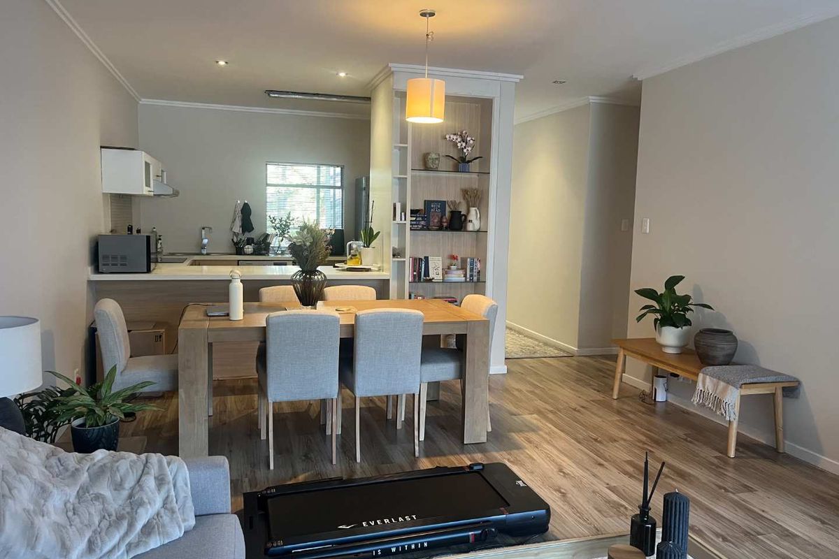 Open-plan living and dining area featuring modern laminate flooring, a built-in display shelf, and a functional kitchen with integrated cabinetry.