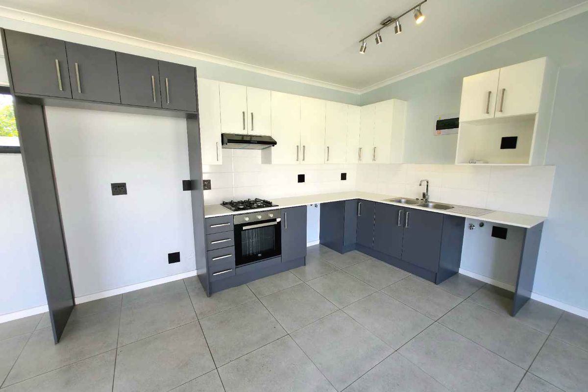 Modern kitchen featuring two-tone cabinetry, built-in oven, gas hob, extractor fan, and tiled flooring.