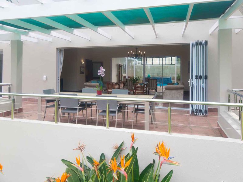 A spacious covered patio featuring a pergola, tiled flooring, and modern stainless steel railings, seamlessly connecting to the indoor living area through bi-fold doors.