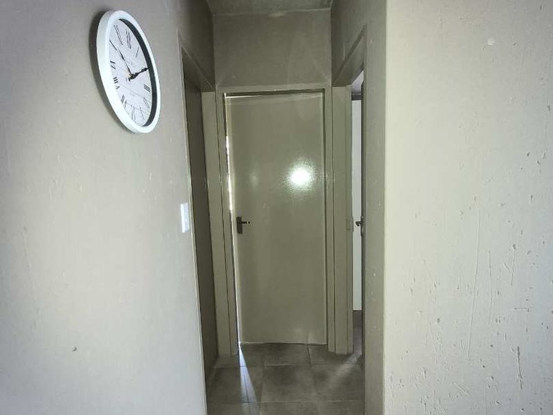 A functional hallway featuring tiled flooring and access to multiple internal rooms, currently requiring cosmetic updates to the walls and ceiling.