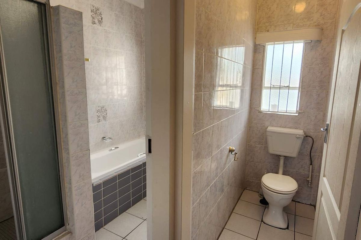 A functional bathroom featuring a separate shower cubicle, a built-in bathtub, and a private toilet area with tiled finishes throughout.