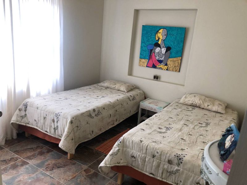 A bedroom featuring tiled flooring and a built-in wall niche, providing a functional space with natural light from the window.