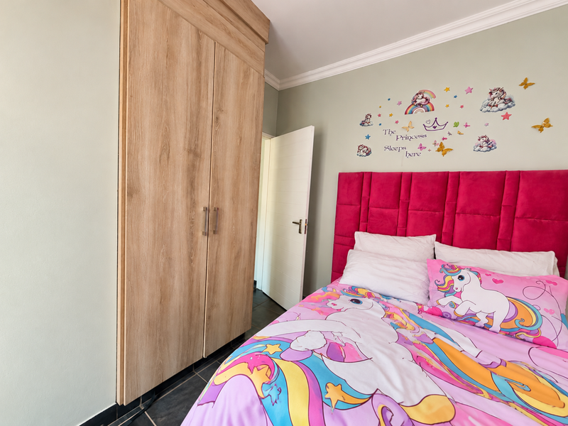 A bedroom featuring a light wood-finish built-in wardrobe, decorative coving, and a pink upholstered headboard.
